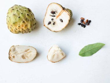 Taze yeşil kremalı elma, elma şekeri, anona cherimola (annona squamosa l.) beyaz arka planda yalıtılmış yapraklarla ikiye bölünmüş meyve. Tropikal egzotik meyve ve sağlıklı meyve