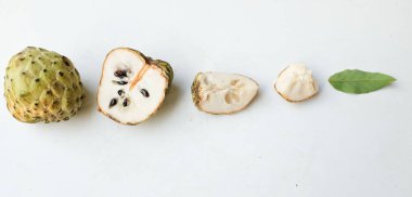 Taze yeşil kremalı elma, elma şekeri, anona cherimola (annona squamosa l.) beyaz arka planda yalıtılmış yapraklarla ikiye bölünmüş meyve. Tropikal egzotik meyve ve sağlıklı meyve