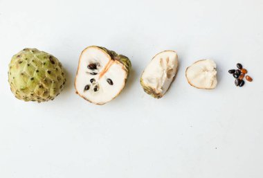 Taze yeşil kremalı elma, elma şekeri, anona cherimola (annona squamosa l.) beyaz arka planda yalıtılmış yapraklarla ikiye bölünmüş meyve. Tropikal egzotik meyve ve sağlıklı meyve