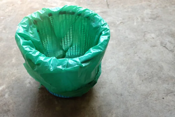 trash can with green plastic bags isolated on the cement floor background.symbol of waste management and environmental
