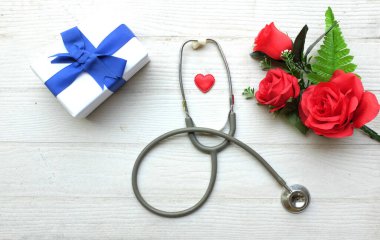 Üst manzara ve fotokopi makinesi, kırmızı güller, steteskop kırmızı kalpler, ahşap masa beyaz arka plan, Sevgililer Günü konsepti. Dünya Sağlık Günü, Doktorlar Günü, Hemşireler Günü