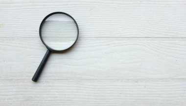 Üst görünüm ve büyüteç büyüteç loupe arama sembolü ahşap masa üzerinde izole beyaz arka fon. İnternet üzerinden bilgi aranıyor, minimal yaratıcı konsept. 