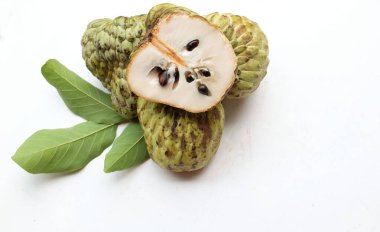 Taze yeşil kremalı elma, elma şekeri, anona cherimola (annona squamosa l.) beyaz arka planda yalıtılmış yapraklarla ikiye bölünmüş meyve. Tropikal egzotik meyve ve sağlıklı meyve
