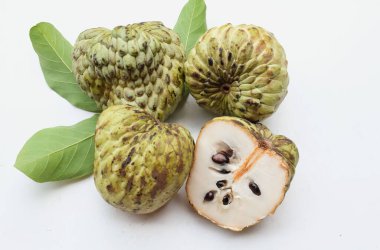 Taze yeşil kremalı elma, elma şekeri, anona cherimola (annona squamosa l.) beyaz arka planda yalıtılmış yapraklarla ikiye bölünmüş meyve. Tropikal egzotik meyve ve sağlıklı meyve