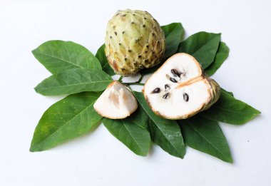 Taze yeşil kremalı elma, elma şekeri, anona cherimola (annona squamosa l.) beyaz arka planda yalıtılmış yapraklarla ikiye bölünmüş meyve. Tropikal egzotik meyve ve sağlıklı meyve
