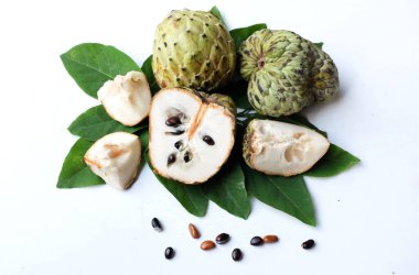 Taze yeşil kremalı elma, elma şekeri, anona cherimola (annona squamosa l.) beyaz arka planda yalıtılmış yapraklarla ikiye bölünmüş meyve. Tropikal egzotik meyve ve sağlıklı meyve