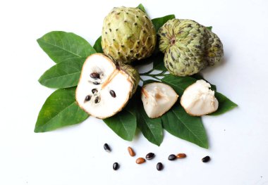 Taze yeşil kremalı elma, elma şekeri, anona cherimola (annona squamosa l.) beyaz arka planda yalıtılmış yapraklarla ikiye bölünmüş meyve. Tropikal egzotik meyve ve sağlıklı meyve