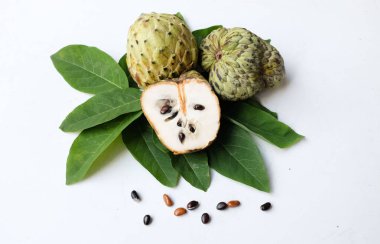 Taze yeşil kremalı elma, elma şekeri, anona cherimola (annona squamosa l.) beyaz arka planda yalıtılmış yapraklarla ikiye bölünmüş meyve. Tropikal egzotik meyve ve sağlıklı meyve