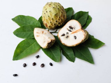 Taze yeşil kremalı elma, elma şekeri, anona cherimola (annona squamosa l.) beyaz arka planda yalıtılmış yapraklarla ikiye bölünmüş meyve. Tropikal egzotik meyve ve sağlıklı meyve