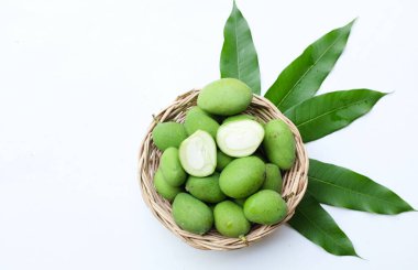 taze çiğ organik mango (Mangifera indica L. Var.) Tahta sepetlerdeki yapraklarla ikiye bölünmüş meyve, beyaz arka planda izole edilmiş. Tropikal egzotik meyve ve sağlıklı meyve