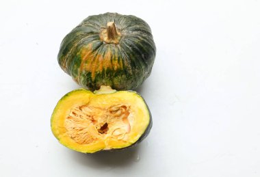 Bir yığın taze çiğ Japon balkabağı (Cucurbita moschata), Kabocha kabağı, hem top ve kesim halinde, beyaz bir sırt üzerinde izole edilmiş sarı eti gösterir. Sağlıklı gıda sebze, meyve ve gıda işi