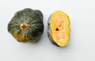 Bir yığın taze çiğ Japon balkabağı (Cucurbita moschata), Kabocha kabağı, hem top ve kesim halinde, beyaz bir sırt üzerinde izole edilmiş sarı eti gösterir. Sağlıklı gıda sebze, meyve ve gıda işi
