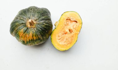 Bir yığın taze çiğ Japon balkabağı (Cucurbita moschata), Kabocha kabağı, hem top ve kesim halinde, beyaz bir sırt üzerinde izole edilmiş sarı eti gösterir. Sağlıklı gıda sebze, meyve ve gıda işi