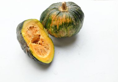 Bir yığın taze çiğ Japon balkabağı (Cucurbita moschata), Kabocha kabağı, hem top ve kesim halinde, beyaz bir sırt üzerinde izole edilmiş sarı eti gösterir. Sağlıklı gıda sebze, meyve ve gıda işi