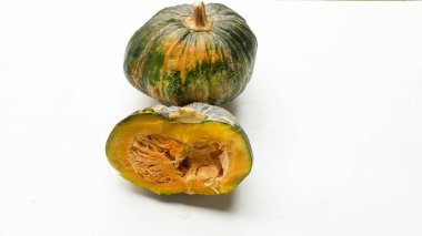 Bir yığın taze çiğ Japon balkabağı (Cucurbita moschata), Kabocha kabağı, hem top ve kesim halinde, beyaz bir sırt üzerinde izole edilmiş sarı eti gösterir. Sağlıklı gıda sebze, meyve ve gıda işi