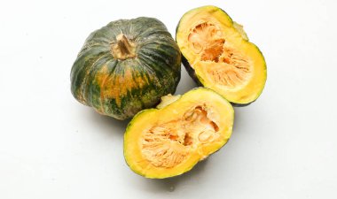 Bir yığın taze çiğ Japon balkabağı (Cucurbita moschata), Kabocha kabağı, hem top ve kesim halinde, beyaz bir sırt üzerinde izole edilmiş sarı eti gösterir. Sağlıklı gıda sebze, meyve ve gıda işi