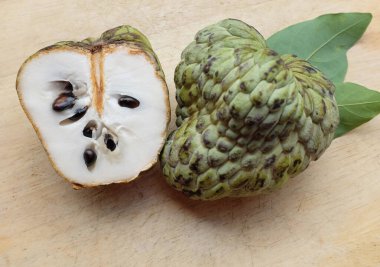 Taze yeşil kremalı elma, elma şekeri, annona cherimola (annona squamosa l.) meyve dilimlenmiş, tahta kesme tahtasının üzerinde soyutlanmış. Tropikal egzotik meyve ve sağlıklı meyve