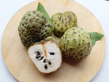 Taze yeşil kremalı elma, elma şekeri, annona cherimola (annona squamosa l.) meyve dilimlenmiş, tahta kesme tahtasının üzerinde soyutlanmış. Tropikal egzotik meyve ve sağlıklı meyve