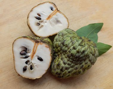 Taze yeşil kremalı elma, elma şekeri, annona cherimola (annona squamosa l.) meyve dilimlenmiş, tahta kesme tahtasının üzerinde soyutlanmış. Tropikal egzotik meyve ve sağlıklı meyve