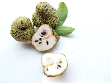 Taze yeşil kremalı elma, elma şekeri, anona cherimola (annona squamosa l.) beyaz arka planda yalıtılmış yapraklarla ikiye bölünmüş meyve. Tropikal egzotik meyve ve sağlıklı meyve