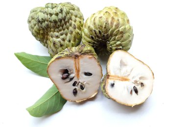 Taze yeşil kremalı elma, elma şekeri, anona cherimola (annona squamosa l.) beyaz arka planda yalıtılmış yapraklarla ikiye bölünmüş meyve. Tropikal egzotik meyve ve sağlıklı meyve