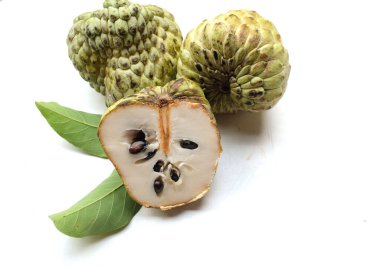 Taze yeşil kremalı elma, elma şekeri, anona cherimola (annona squamosa l.) beyaz arka planda yalıtılmış yapraklarla ikiye bölünmüş meyve. Tropikal egzotik meyve ve sağlıklı meyve