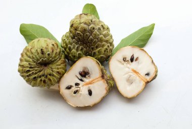 Taze yeşil kremalı elma, elma şekeri, anona cherimola (annona squamosa l.) beyaz arka planda yalıtılmış yapraklarla ikiye bölünmüş meyve. Tropikal egzotik meyve ve sağlıklı meyve