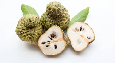 Taze yeşil kremalı elma, elma şekeri, anona cherimola (annona squamosa l.) beyaz arka planda yalıtılmış yapraklarla ikiye bölünmüş meyve. Tropikal egzotik meyve ve sağlıklı meyve