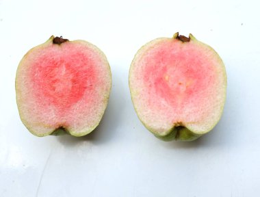 tatlı olgun pembe guava, kırmızı guava (psidyum guajava) yeşil yapraklı ve yarım dilimli meyve, beyaz zemin üzerinde tamamen izole edilmiş, üst görünüm, düz uzanmış, sağlıklı meyve kavramı