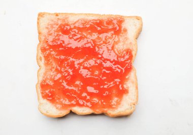 Çilek reçelinin kuş bakışı görüntüsü, beyaz bir arkaplanda izole edilmiş bir ekmek dilimine serpilmiş taze kırmızı böğürtlen. Sağlıklı atıştırmalıklar ve yemek fikirleri