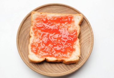 Ahududu çileği reçelinin kuş bakışı görüntüsü, beyaz bir zeminde izole edilmiş ahşap bir tabakta taze kırmızı böğürtlen dilimi üzerine yayılmış. Sağlıklı atıştırmalıklar ve yemek fikirleri