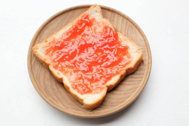 Ahududu çileği reçelinin kuş bakışı görüntüsü, beyaz bir zeminde izole edilmiş ahşap bir tabakta taze kırmızı böğürtlen dilimi üzerine yayılmış. Sağlıklı atıştırmalıklar ve yemek fikirleri