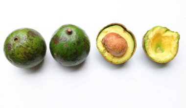 Taze, olgun avokado Alpukat veya Avokado (Persea americana) meyvesi, beyaz arka planda izole edilmiş yapraklarla ikiye bölünmüş. Tropikal egzotik meyve ve sağlıklı meyve