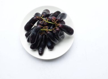 Bir demet taze çekirdeksiz ay çekirdeği üzümü, Mor Cadı Parmak üzümü, Sapphire üzümleri ya da beyaz arkaplanda izole edilmiş beyaz seramik bir elmaye üzümü. Siyah üzümler.. 