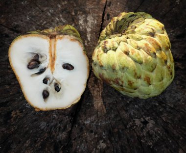 Taze yeşil kremalı elma, elma şekeri, anona cherimola (annona squamosa l.), tahta bir arka planda yapraklarla ikiye bölünmüş meyve. Tropikal egzotik meyve ve sağlık