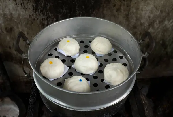close up a homemade of steamed buns ( Chinese steamed buns ) ,stuffed steamed bun with pork filling, cream, sweet, red pork ,red beansin the steam pot . it taste delicious and suitable for breakfast.