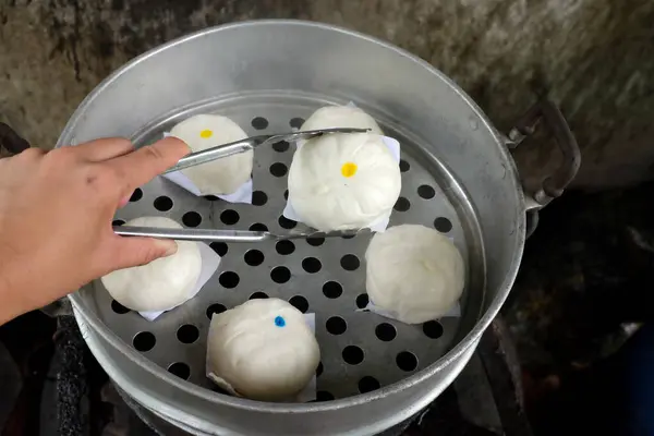 womanUse tongs to squeeze of steamed buns ( Chinese steamed buns ) ,stuffed steamed bun with pork filling, cream, sweet, red pork ,red beans in the steam pot . it taste delicious and suitable for bre
