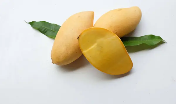 stock image ripe yellow mango golden ,mango nam dok mai mango ,barracuda mango ( mangifera indica) king of fruit cut in half sliced with leaves isolated on a  white backdrop.tropical exotic fruit and healthyfruit