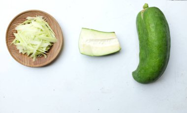 Tayland 'da papaya salatası ya da Som Tam menüsünü hazırlamak için beyaz bir arka planda tahtadan bir tabakta doğranmış papaya eriştesi ya da doğranmış çiğ papaya. Papaya salatası baharatlı, Tayland yemeği, geleneksel Tayland yemeği. 