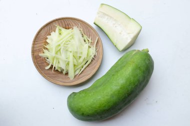 Tayland 'da papaya salatası ya da Som Tam menüsünü hazırlamak için beyaz bir arka planda tahtadan bir tabakta doğranmış papaya eriştesi ya da doğranmış çiğ papaya. Papaya salatası baharatlı, Tayland yemeği, geleneksel Tayland yemeği. 