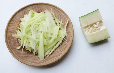 Tayland 'da papaya salatası ya da Som Tam menüsünü hazırlamak için beyaz bir arka planda tahtadan bir tabakta doğranmış papaya eriştesi ya da doğranmış çiğ papaya. Papaya salatası baharatlı, Tayland yemeği, geleneksel Tayland yemeği. 