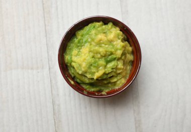 Lezzetli püre olmuş yeşil avokado, avokado kreması, ezilmiş avokado sosu, mezenin içinde atıştırmalık olarak servis edilen guacamole veya ahşap bir masa arkasında vejetaryen diyeti.