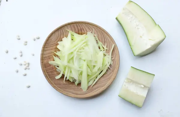 Tayland 'da papaya salatası ya da Som Tam menüsünü hazırlamak için beyaz bir arka planda tahtadan bir tabakta doğranmış papaya eriştesi ya da doğranmış çiğ papaya. Papaya salatası baharatlı, Tayland yemeği, geleneksel Tayland yemeği. 