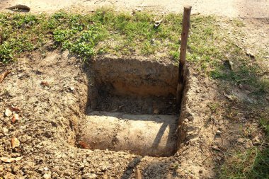 Beton pili yerleştirmek için çukur kazdık. Dikdörtgen şeklinde çukur kazdık. Dokuya yakın çekim. Çimlerin ortasında kare şeklinde bir delik..
