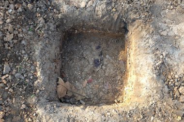 Beton pili yerleştirmek için çukur kazdık. Dikdörtgen şeklinde çukur kazdık. Dokuya yakın çekim. Çimlerin ortasında kare şeklinde bir delik..
