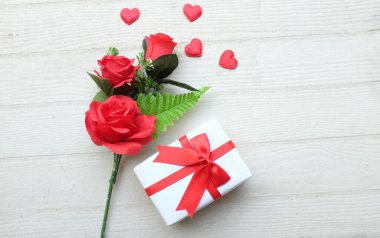 Bir buket güzel kırmızı gül çiçeği ve bir sürü kırmızı kalp, ahşap zemin üzerinde kopyalanmış yer veya metin, afiş, hediye, Sevgililer Günü kutlaması.