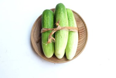 Salatalıklar (salatalık sativus) yeşil sebzeler bir tabak ahşap üzerinde izole beyaz bir sırt üzerinde. Sağlıklı meyve, sebze, yiyecek konsepti