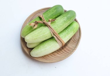 Salatalıklar (salatalık sativus) yeşil sebzeler bir tabak ahşap üzerinde izole beyaz bir sırt üzerinde. Sağlıklı meyve, sebze, yiyecek konsepti