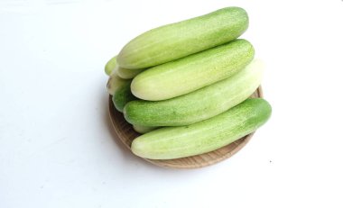 Salatalıklar (salatalık sativus) yeşil sebzeler bir tabak ahşap üzerinde izole beyaz bir sırt üzerinde. Sağlıklı meyve, sebze, yiyecek konsepti