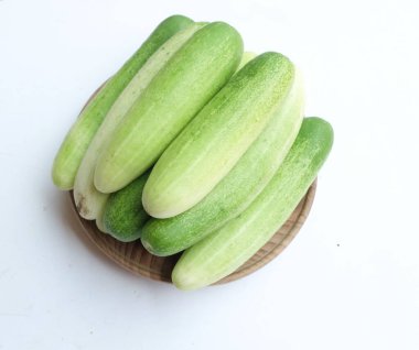 Salatalıklar (salatalık sativus) yeşil sebzeler bir tabak ahşap üzerinde izole beyaz bir sırt üzerinde. Sağlıklı meyve, sebze, yiyecek konsepti